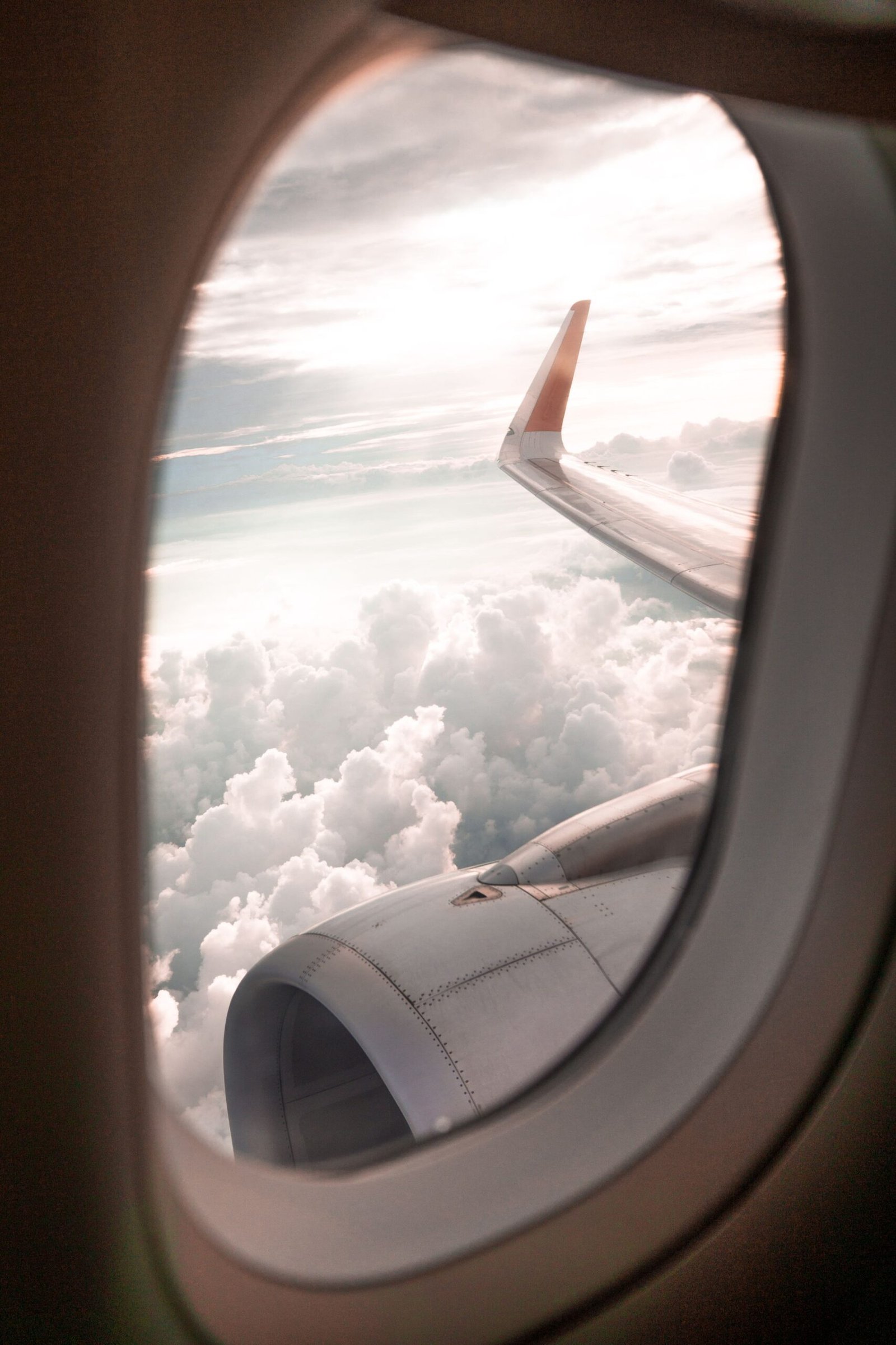 Airplane wing and clouds seen through a cabin window at golden hour